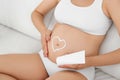 Heart painted with body cream on pregnant woman`s belly at home Royalty Free Stock Photo