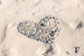 Heart of pebbles on a beach partly covered with sand