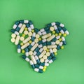 Heart of pills and capsules on green background Royalty Free Stock Photo