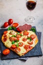 Heart pizza with mozzarella and tomatoes on slate with wine. Valentine`s day date food concept