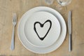 Heart on a plate. Wood table. Cutlery. Knife, fork. Glasses. Suitable as a background. For the menu. We love with love. Royalty Free Stock Photo