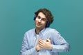 From the heart. Portrait of a young beautiful man wearing white t-shirt and blue shirt in blue headphones holding his hand on Royalty Free Stock Photo