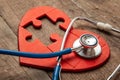Heart puzzle red and stethoscope on wooden background. Concept diagnosis and treatment of heart disease, medical insurance Royalty Free Stock Photo