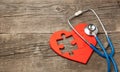 Heart puzzle red and stethoscope on wooden background. Concept diagnosis and treatment of heart disease, medical insurance Royalty Free Stock Photo