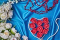 Heart of red flower buds on a blue beautiful fabric with beads of pearls and coral top view Royalty Free Stock Photo