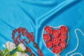 Heart of red flower buds on a blue beautiful fabric with beads of pearls and coral top view Royalty Free Stock Photo