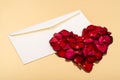 Heart of red petals lying on top of an open blank envelopes