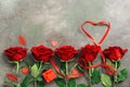 Heart of red ribbon and a border of red roses on a dark rustic background. Valentine`s Day. Top view, flat lay, copy space Royalty Free Stock Photo