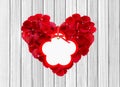Heart from red rose petals and tag on wooden table Royalty Free Stock Photo