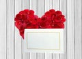 Heart from red rose petals and white card on wooden table Royalty Free Stock Photo
