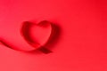 Heart from satin ribbon on red background with copy space, top view. Decor for Valentine`s day or wedding. Concept love Royalty Free Stock Photo