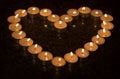 Heart shape arrangement of burning tea lights on a dark background. 3 Royalty Free Stock Photo