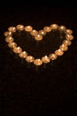 Heart shape arrangement of burning tea lights on a dark background. 7 Royalty Free Stock Photo