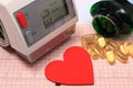 Heart shape, blood pressure monitor and tablets on electrocardiogram Royalty Free Stock Photo