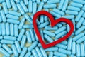 heart shape and blue capsules. Importance of medication treatment