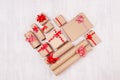 Heart shape of christmas presents of craft paper gifts with red ribbons and bows on soft light white wood board, flat lay. Royalty Free Stock Photo