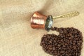 Heart shape coffee beans spilled from traditional Turkish copper coffee pot on a burlap Royalty Free Stock Photo