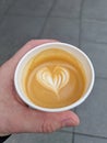 Heart shape on coffee foam. Take away coffee macchiato holds a hand. Royalty Free Stock Photo