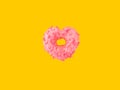 Heart shape donut glazed with pink strawberry icing sugar sprinkles floating in air on yellow background. Creative food poster Royalty Free Stock Photo