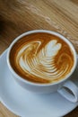 Heart shape foam drawed on hot fresh coffee latte art on wooden table at vintage cafe