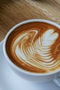 Heart shape foam drawed on hot fresh coffee latte art on wooden table at vintage cafe