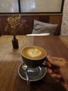 Heart shape foam drawed on hot fresh coffee latte art on wooden table at vintage cafe