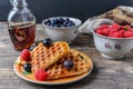 Heart shape gaufre with maple syrup and forest fruits on rustic wooden table