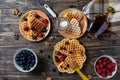 Heart shape gaufre with maple syrup and forest fruits on rustic wooden table