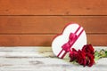 Heart shape gift box and red roses on aged wooden table Royalty Free Stock Photo