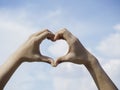 Heart shape hand on blue sky and fluffy cloud background. Royalty Free Stock Photo