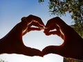 Heart shape hand displaye on sky background with sun light reflection