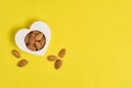 Heart shape and handful of almonds yellow background.