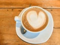 Close up heart shape of latte art on hot coffee cup on wooden table in cafe Royalty Free Stock Photo