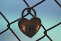 Heart shape lock tied to a grid rusty wire fence