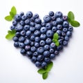 Heart shape made from blueberries with green leaves, isolated on white background