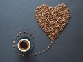 Heart shape made of coffee beans and a cup of black coffee on black background Royalty Free Stock Photo