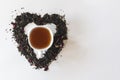 Heart shape made with a mixture of a variety of dried tea leaves and a cup of black tea Royalty Free Stock Photo