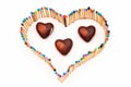 a heart shape made of multicolored matchsticks with heart-shaped candies