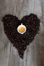 Heart shape made out of coffee beans on top of a table with an espresso cup in the middle Royalty Free Stock Photo