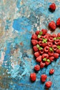 Heart shape made of premium raspberries on a blue background. Close up, top view. Romantic concept.