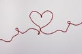 Heart shape made with red thread. Valentine`s day, love message on light pink white background Royalty Free Stock Photo