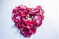 A heart shape made with rose petals celebrating the VALENTINE`S DAY on a silver/white wooden surface. Royalty Free Stock Photo