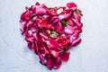 A heart shape made with rose petals celebrating the VALENTINE`S DAY on a silver/white wooden surface. Royalty Free Stock Photo