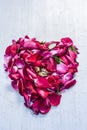 A heart shape made with rose petals celebrating the VALENTINE`S DAY on a silver/white wooden surface. Royalty Free Stock Photo