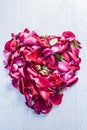 A heart shape made with rose petals celebrating the VALENTINE`S DAY on a silver/white wooden surface. Royalty Free Stock Photo