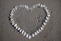 Heart shape made of seashells arranged on sandy beach background Royalty Free Stock Photo