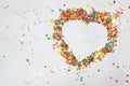 Heart shape made from small colorful candies on a white marble background. Valentine day. About love