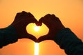 Heart shape making of hands against bright sea sunset Royalty Free Stock Photo