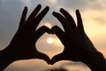 Heart shape making of hands against bright sea sunset Royalty Free Stock Photo
