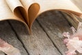 Heart shape from opened book pages on wood background. Royalty Free Stock Photo